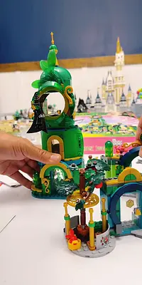 A colorful LEGO set featuring a green tower and tree structure, with a castle in the background.