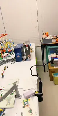 A cluttered desk with LEGO models, boxes, and a phone holder.