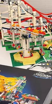 A LEGO roller coaster with a swing ride, built on a green baseplate, next to a Snow White and the Seven Dwarfs box.